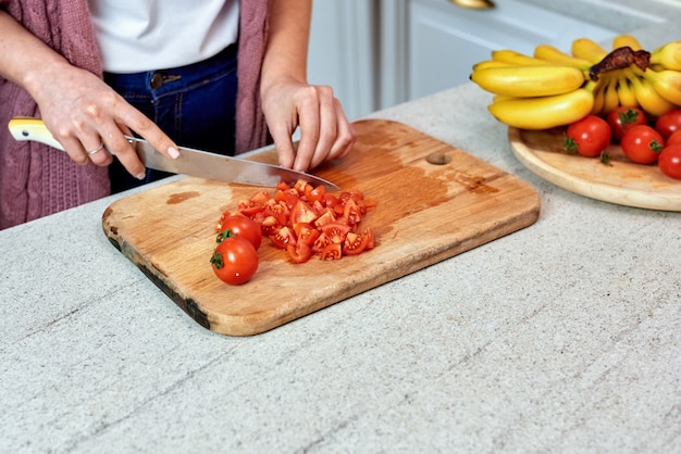 A woman in the kitchen cutting tomatoes for salad