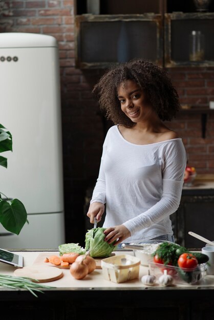 Woman in kitchen cutting vegetable