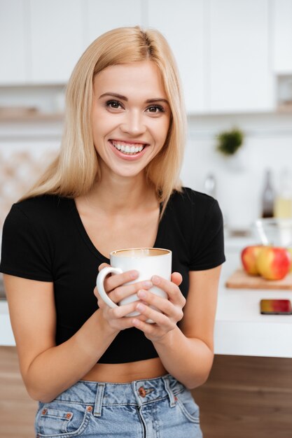 キッチンとカップコーヒーを保持している女性