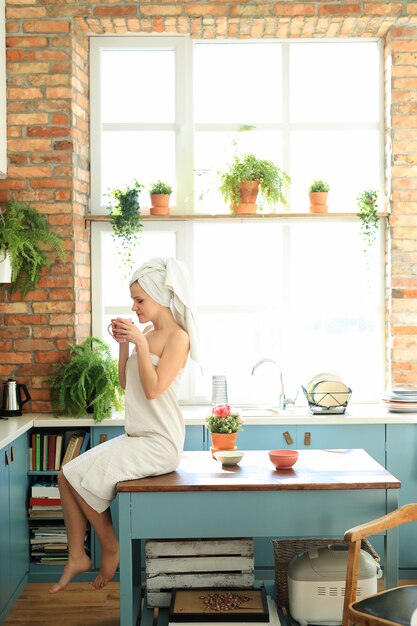 Woman in the kitchen with towel on her head after shower