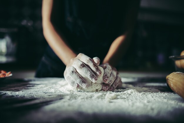 Woman kneads dough for make pizza on wooden. Cooking concept.