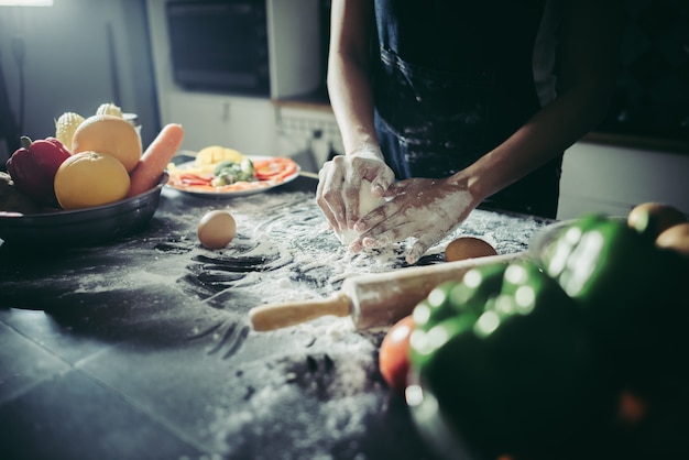 Woman kneads dough for make pizza on wooden. Cooking concept.