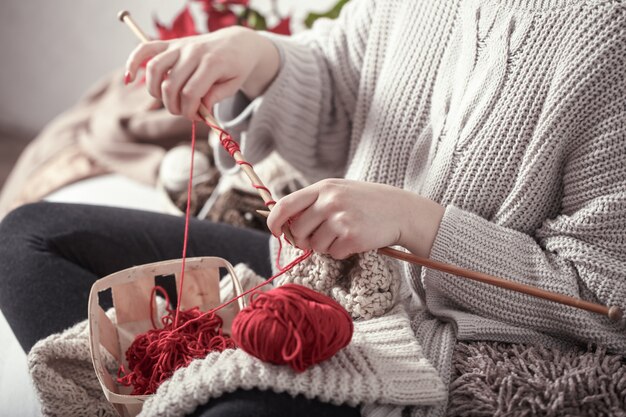 女性はソファの上で編み針を編む