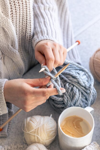 Una donna a maglia con un filo grigio in primo piano