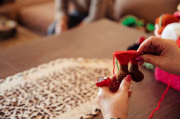 赤い糸で飾りを編み物をする女
