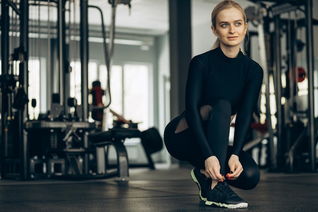 Free photo woman lacing sneakers at the gym