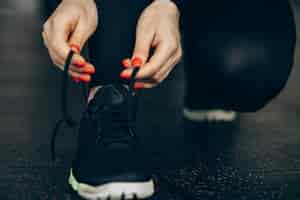 Free photo woman lacing sneakers at the gym