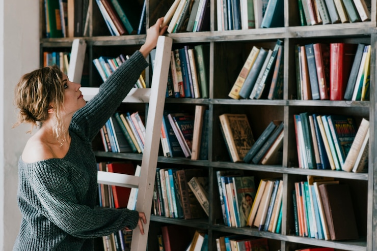 Free Photo woman on ladder taking book