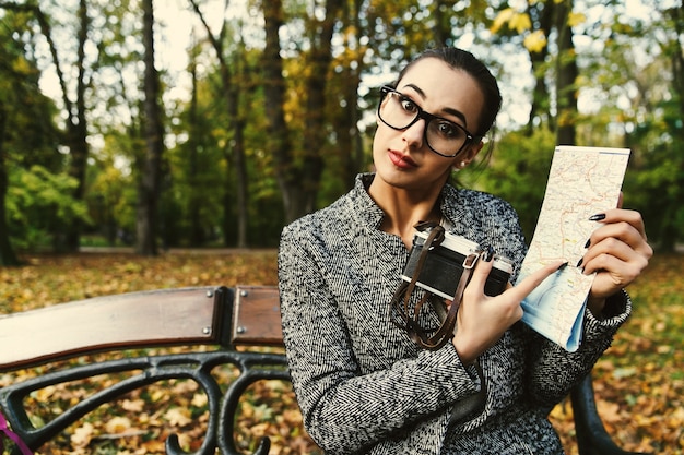 Free photo woman in large glasses stands with camera and a touristic map