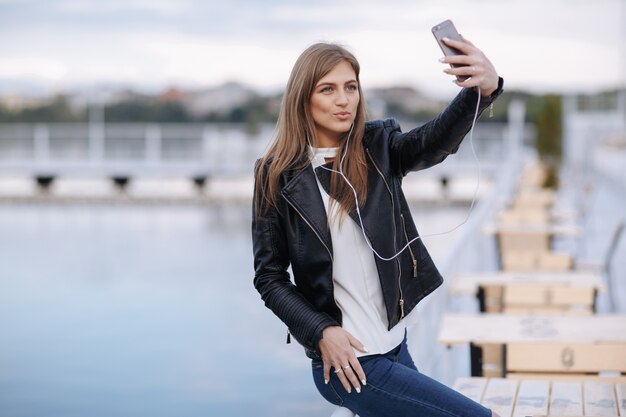 Woman laughing leaning on a railing making an auto photo