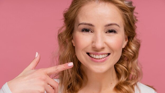 Woman laughing pointing at her smile