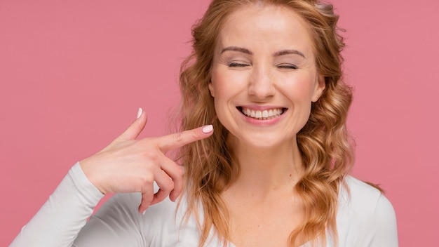 Woman laughing pointing at her smile