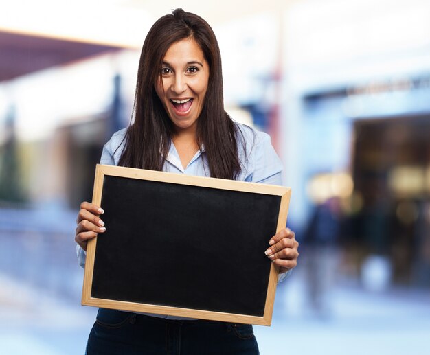 Woman laughing with open mouth holding a blackboard