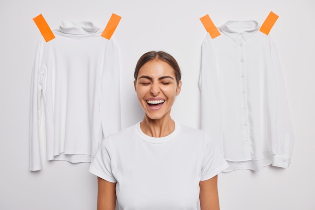 La donna ride felicemente tiene gli occhi chiusi vestita con una maglietta casual in posa su bianco con dolcevita intonacato e camicia che si veste per la passeggiata in strada. persone e abbigliamento