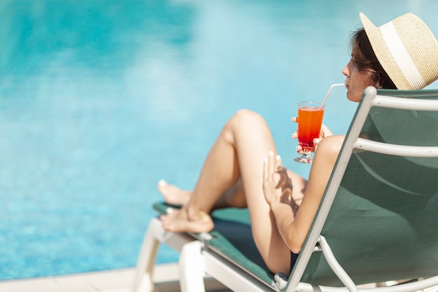 Woman laying on sunbed enjoying drink