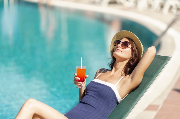 Free photo woman laying on sunbed holding drink