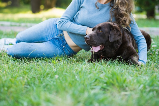 Woman leaning on dog over green grass