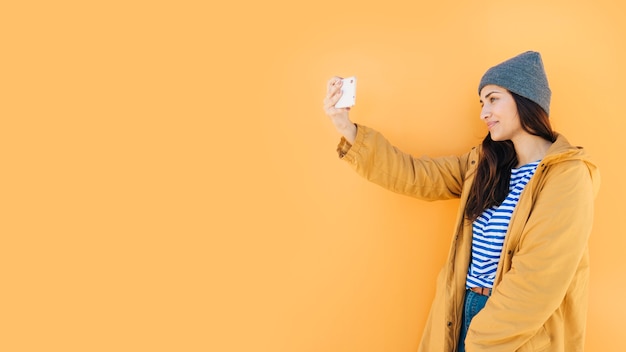 Foto gratuita donna che si appoggia sulla superficie prendendo selfie sul cellulare