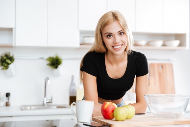 Woman leaning on a table while standing at the kitchen