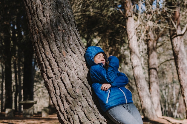 Woman leaning on tree in woods