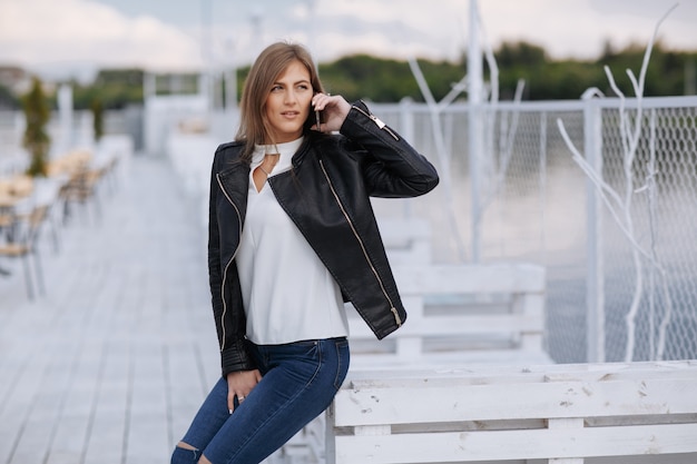 Woman leaning on a white wooden board talking on the phone