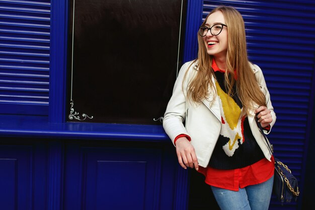 Woman leans to a blue door standing on the street 