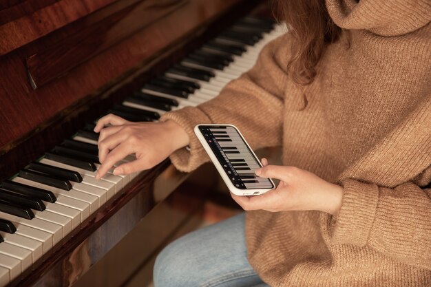 女性は自分の携帯電話のアプリケーションを使用してピアノを弾くことを学びます