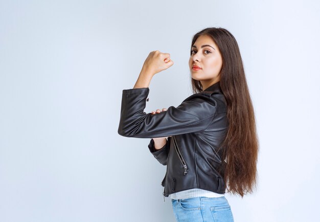 woman in leather jacket demonstrating her arm muscles.