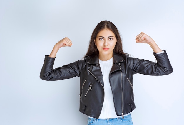 woman in leather jacket demonstrating her arm muscles.