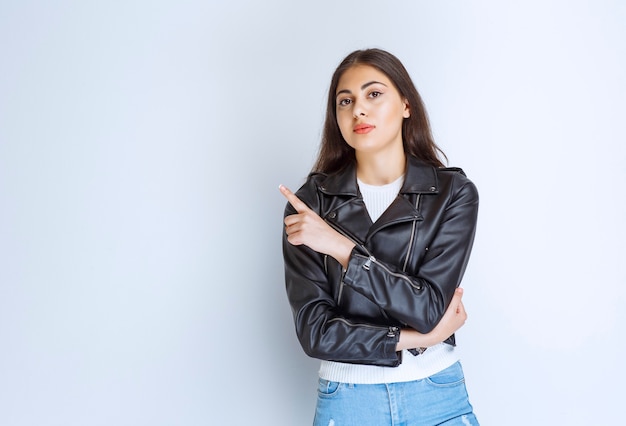 woman in leather jacket pointing at something on the left side.