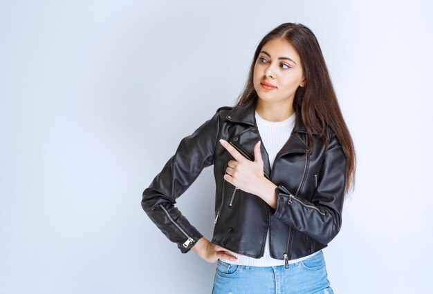 woman in leather jacket pointing at something on the left side.