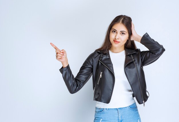 woman in leather jacket pointing at something on the left side.