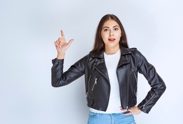 woman in leather jacket pointing at something above.