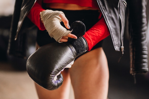 Free photo woman in leather jacket puts on boxing gloves