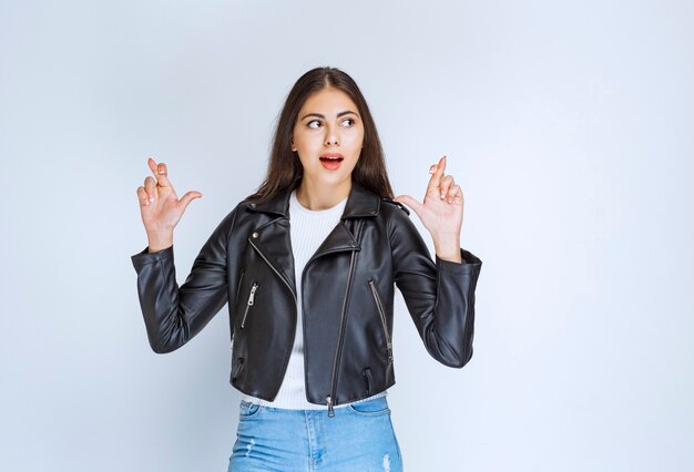 woman in leather jacket showing finger cross.