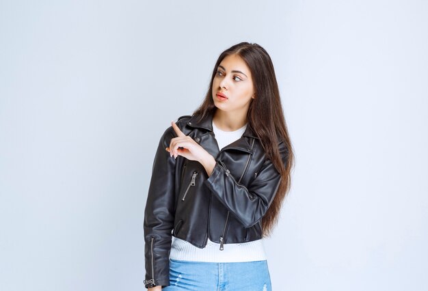 woman in leather jacket showing something behind.