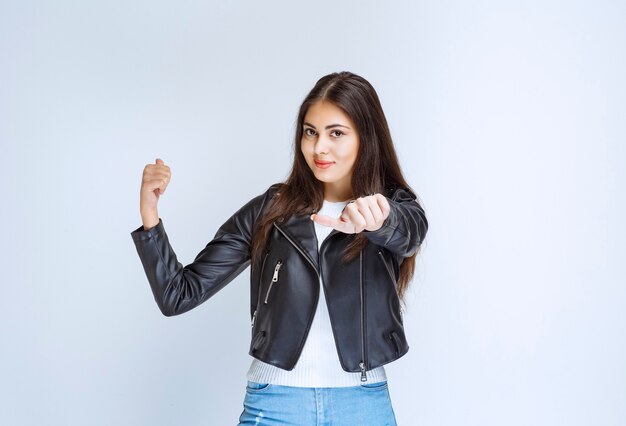 woman in leather jacket showing something behind.