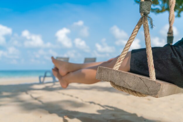 Женщина ноги на качелях на тропический морской пляж