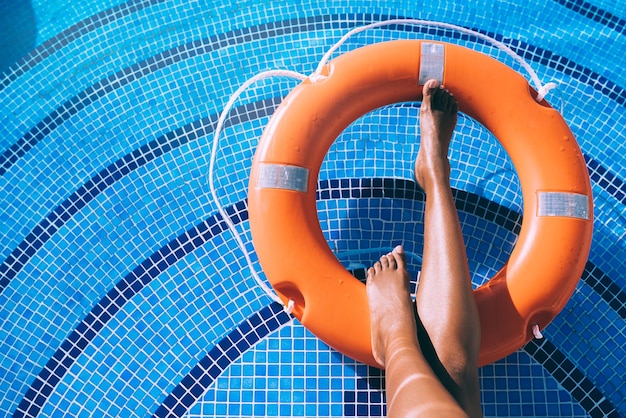 Gambe di donna in una piscina con salvagente