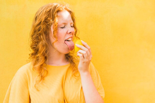 Woman licking lemon medium shot