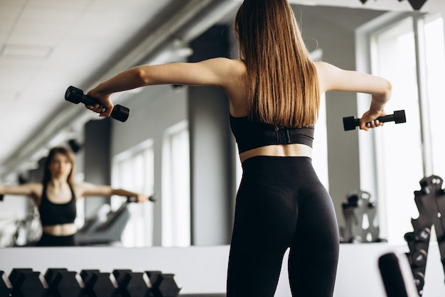 Free photo woman lifting dumbbells at the gym