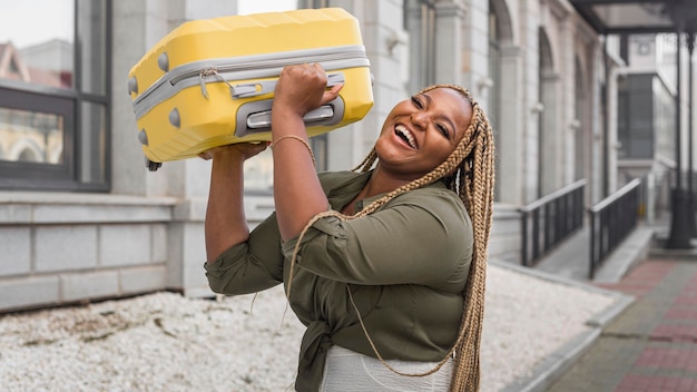 Woman lifting her yellow luggage