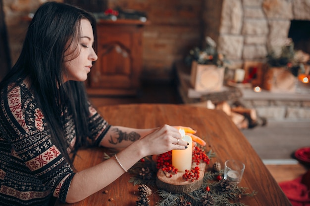 Woman lighting a candle on a wooden table