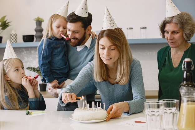 Woman lights candles on the birthday cake Old woman and her adult son stay behind