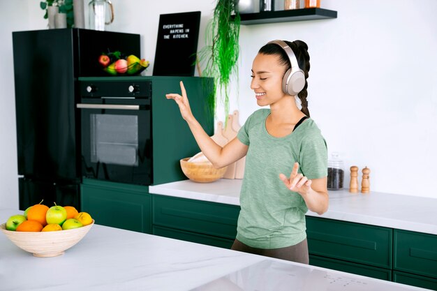 Женщина слушает музыку на зеленой кухне