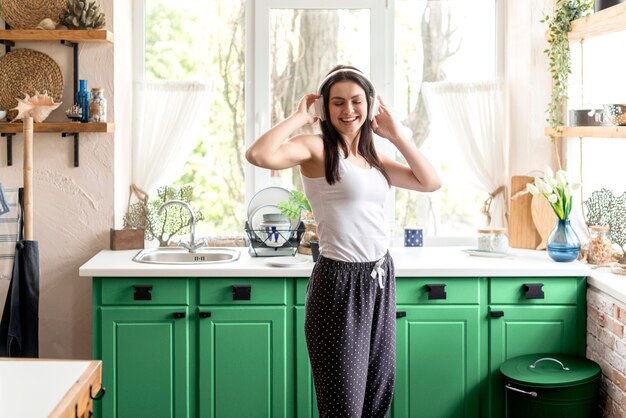 Woman listening to music in a green kitchen