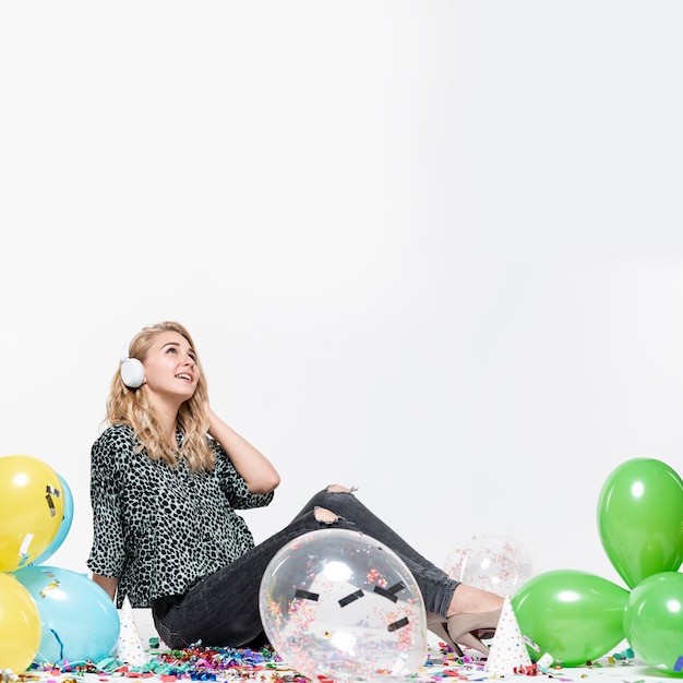 Woman listening to music surrounded by balloons