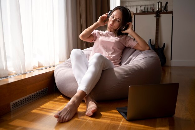 Женщина, слушающая музыку через наушники дома
