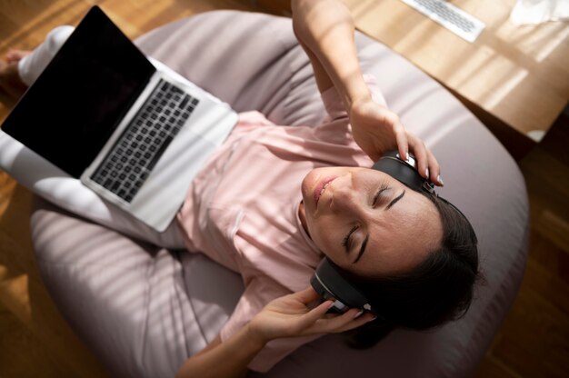 Woman listening to music through headphones at home