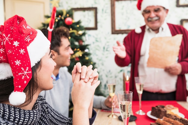 Woman listening to old man greeting at festive table 